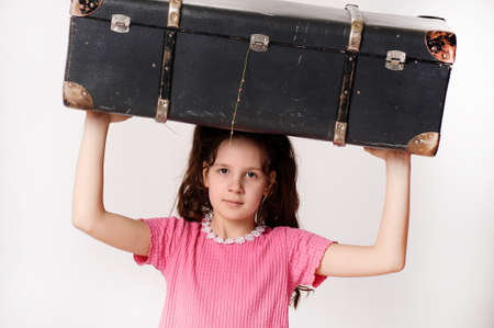 Girl holding a vintage suitcase on head.の写真素材