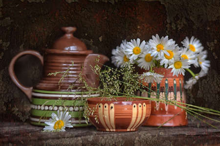 Ceramic tableware and chamomile on a wooden table.の写真素材