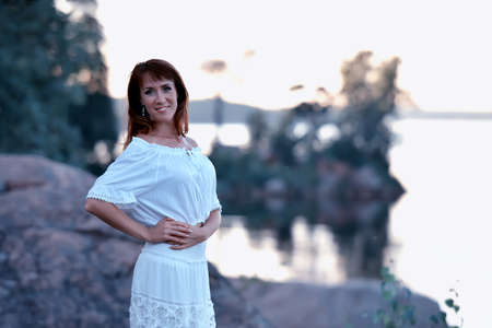 Brunette bride in a wedding dress near lake