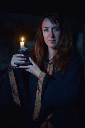 Portrait of a woman in the dark with a candle in hands.の写真素材
