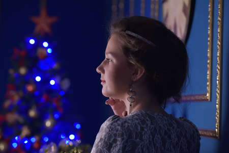 Teen girl in Christmas at the beautiful Christmas tree glowing in the dark.