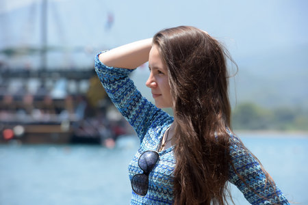 Beautiful young girl on a background of a sailing boat on the sea in water.