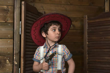 Little boy in cowboy hat with gun in hands
