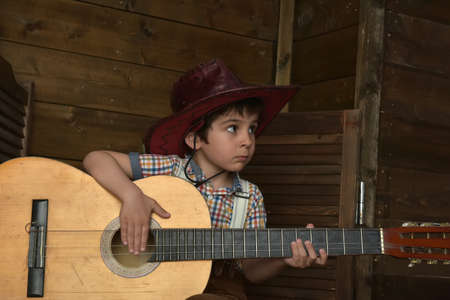 Little boy in cowboy hat with guitar in handsの写真素材