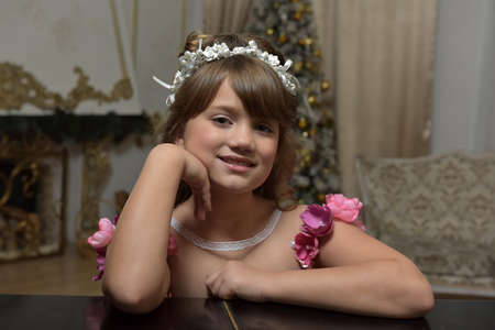 Young girl portrait leaning on hands in a white wreathの写真素材