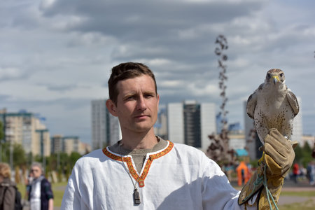 Russia, St. Petersburg, 10,06,2018 A man with a falcon on his hand in Slavic national clothes at the festival of Slavic culture, timed to celebrate the Day of Russiaのeditorial素材