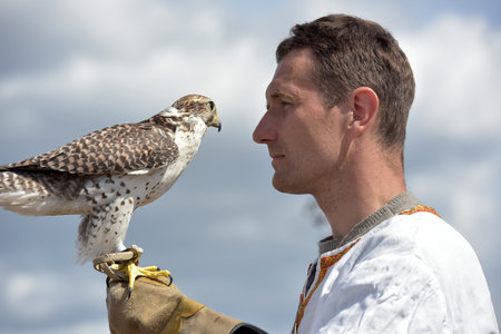 Russia, St. Petersburg, 10,06,2018 A man with a falcon on his hand in Slavic national clothes at the...