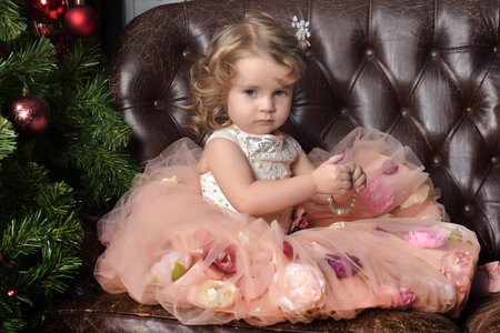 cute little girl on a leather sofa at christmasの写真素材