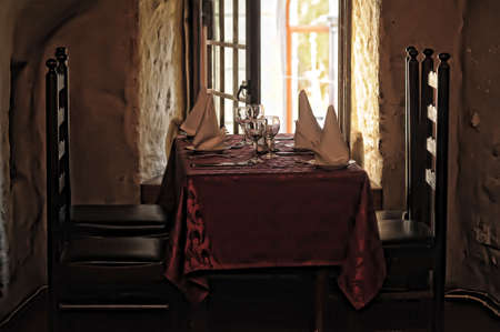 restaurant table with red tablecloth and wooden chairsの写真素材
