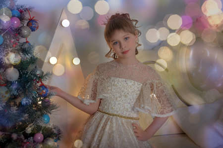 cute girl princess in alabaster victorian dress by christmas tree in christmasの写真素材