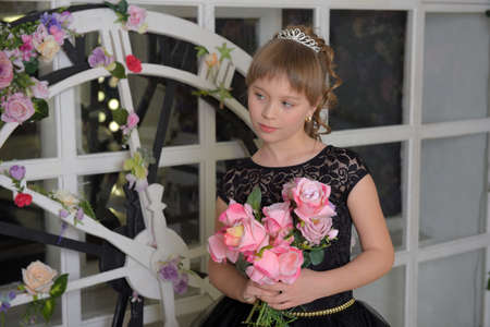 cute girl princess in a black dress with a becket of flowers in her handsの写真素材