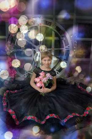 cute girl princess in a black dress with a becket of flowers in her handsの写真素材