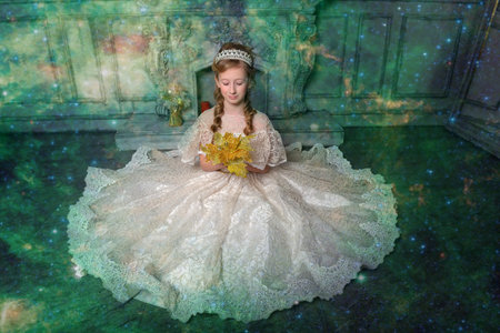 a girl in an elegant white dress with a diadem in her hair and a bouquet of gold flowers in her...