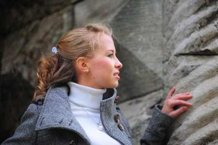 Beautiful girl in a gray coat near the column