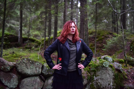 red-haired woman in a black leather jacket in the forest
