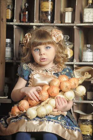 little girl in a dress and apron plays in a vintage kitchenの写真素材