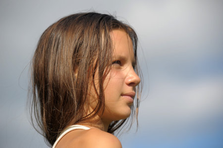portrait of a young girl with long hair on a background of the sky