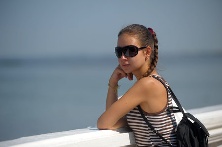 young girl teenager in the summer in a striped T-shirt and sunglasses