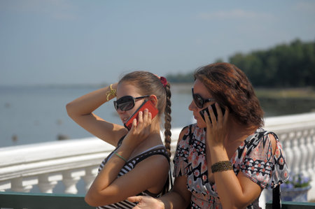 mother with daughter teenager in sunglasses talking on mobile phones in the summer