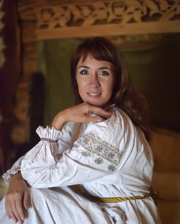 brunette with medieval simple dress sits on the bedの写真素材
