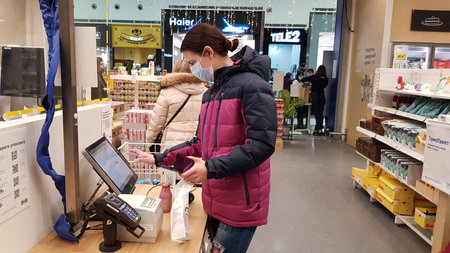 Russia, St. Petersburg 01/02/2021 Buyer in a mask at a self-checkout counter during the coronavirus...