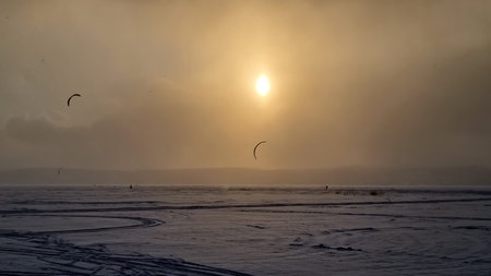Winter landscape. A view of the frozen snow-covered lake. Forest in the background. Stormy evening...