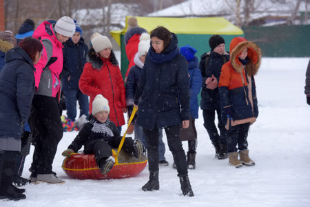 Russia, St. Petersburg 03/08/2021 Riding a roller coaster. Toddler walking in the snow in winter. The child laughs and smiles in winter park.のeditorial素材