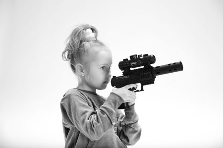 little blond girl with guns, in the studioの写真素材
