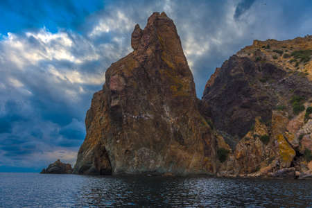 rocks of Cape Fiolent against the background of the evening sky with clouds view from the waterの写真素材