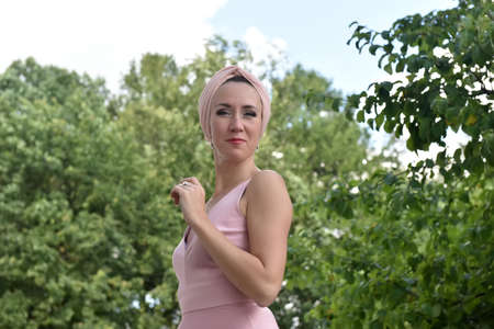 beautiful elegant brunette woman in pink dress outdoorの写真素材