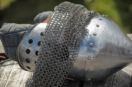 medieval knightly equipment, including a conical helmet with rivets, a chainmail aventail and a balaclava made of thick fabric. The helmet is made of metal, polished and has ventilation holes. The chainmail aventail is designed to protect the neck and shoulders from weapon blows.

This element of armor is typical for medieval Europe and was widely used by knights and warriors in battle. Perhaps this is part of the ammunition used in historical reconstructions or museum exhibitions.の写真素材