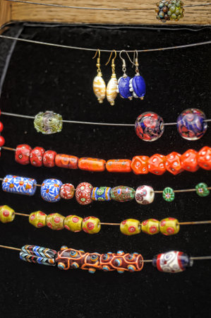 bright and colorful handmade glass beads, placed on threads for display. The multi-colored elements...