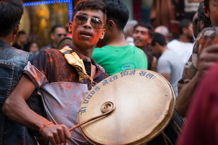 Young man celebrating Diwali / Deepwali / Tihar with friends dancing while playing the drums to music in a street in Kathmanduのeditorial素材