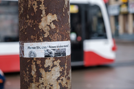 Toronto, ON Canada 12/27/2019:  Anti-poverty sign on rusted electrical pole with a TTC streetcar in...