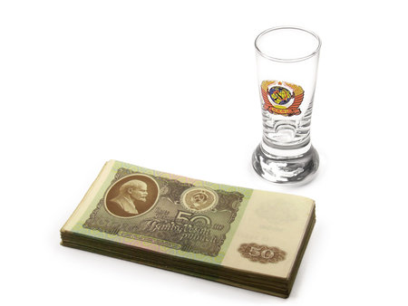 Stack of Soviet 1961 fifty rubles and a vodka glass with USSR national emblem isolated on a white background.の写真素材