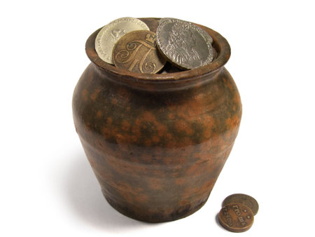 Aged jug with very old silver and copper coins isolated on white background.の写真素材