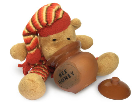 Hungry teddy bear looking into the empty honey pot.の写真素材