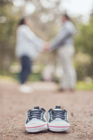 Future mom and dad with little baby shoesの写真素材