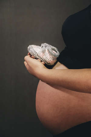 Pregnant carrying baby shoes , Woman Pregnancy Maternity Concept, Female Mother Stomachの写真素材