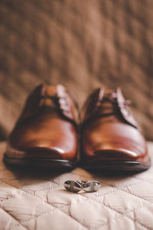 Cuff links and shoes on a brown backgroundの写真素材