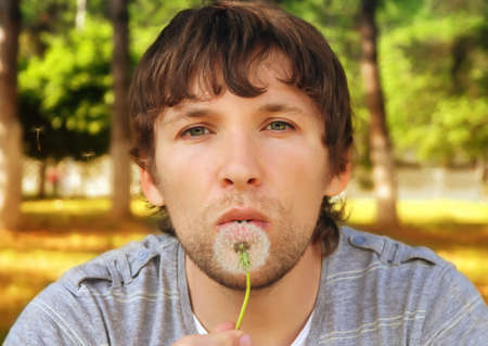 Man blowing Dandelion charming outdoorの写真素材