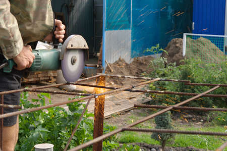 Angle Grinder Metal sawing with flashing sparks close up and Repairman hands home repair garden working summer time  Also called Circular Saw handheld electric instrumentの写真素材