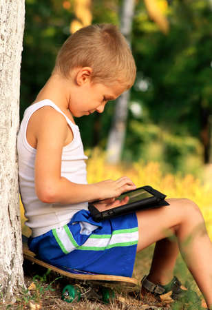 Boy Child playing with Tablet PC Outdoor with forest on background Computer Game Dependence conceptの写真素材