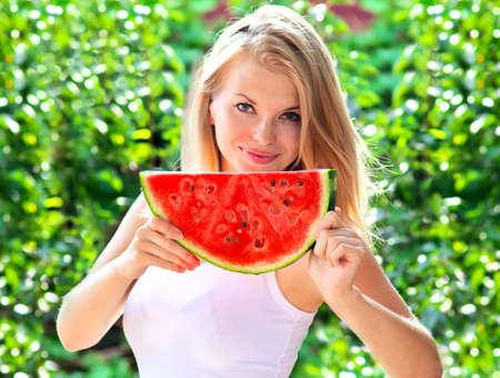 Young Woman with big slice Watermelon Berry fresh in hands Beautiful Smiling Face and Blonde Hair with green nature on background Organic Food conceptの写真素材
