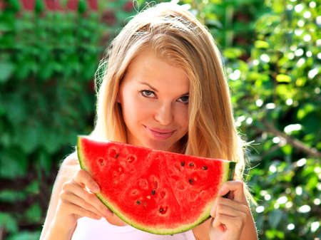 Young Woman with big slice Watermelon Berry fresh in hands Beautiful Smiling Face and Blonde Hair with green nature on background Organic Food conceptの写真素材