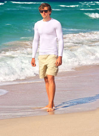 Handsome Man walking on the Beach Seaside sand with blue Sea on background Summer Travelling Tropical islandの写真素材