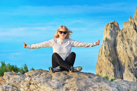 Woman Traveler Relaxing Yoga Meditation sitting on stones relaxing with Rocky Mountain peak Ai-Petri and blue sky on Backgroundの写真素材