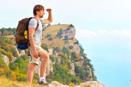 Man Traveler with backpack looking forward outdoor with hands up mountains on background Freedom and Healthy Lifestyle Hiking conceptの写真素材