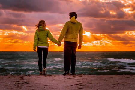 Couple Man and Woman in Love walking on Beach seaside holding hand in hand with Beautiful Sunset sky scenery People Romantic relationship and Friendship conceptの写真素材