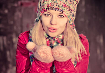 Young Woman Beautiful Winter time wearing knitted hat and gloves and blowing air kiss Lifestyle Expression emotions concept and Christmas holiday trendy colorsの写真素材